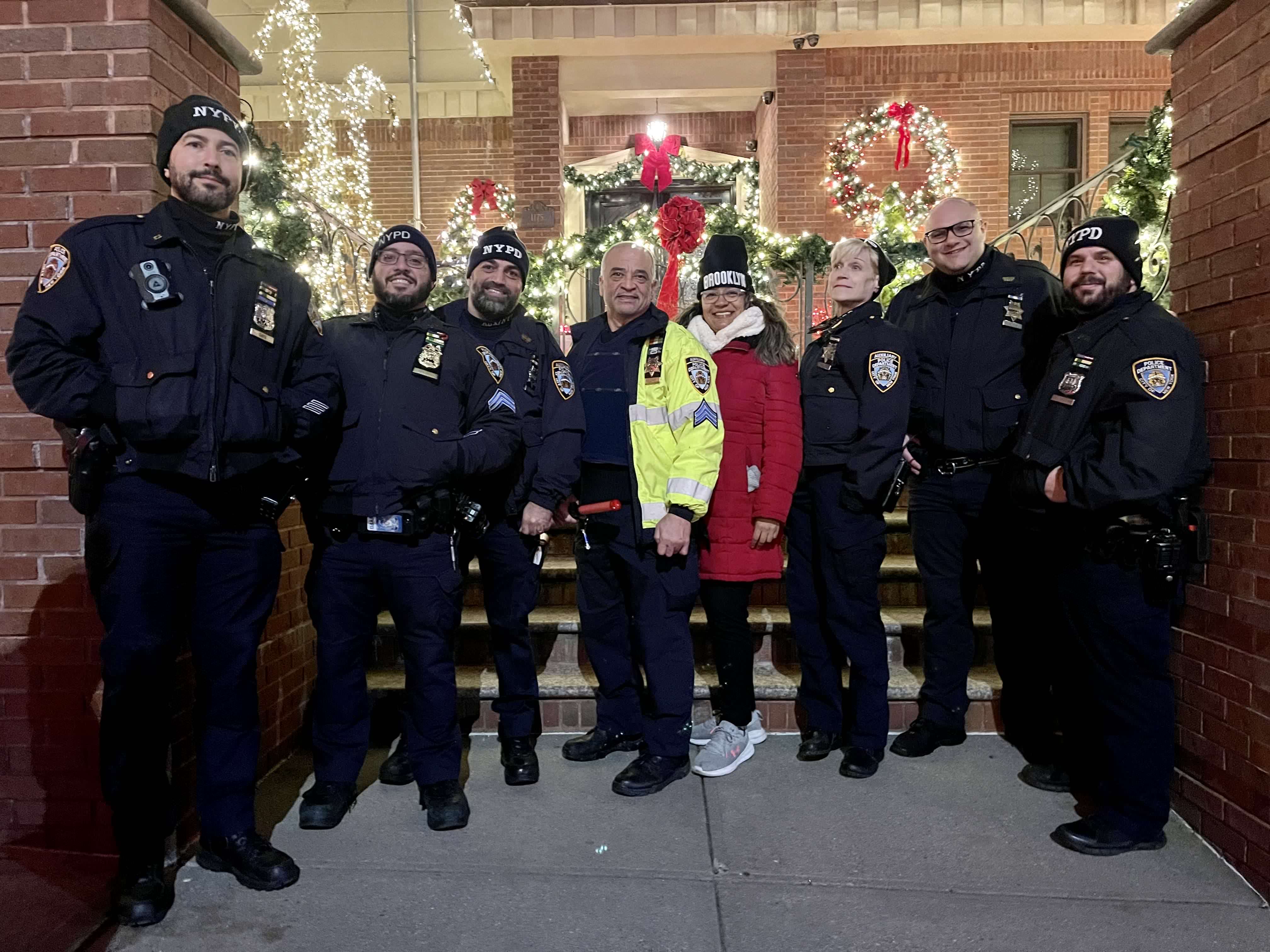 Galios Diaz with NYPD Auxiliary team members at Christmas time next to a wreath and some lights.