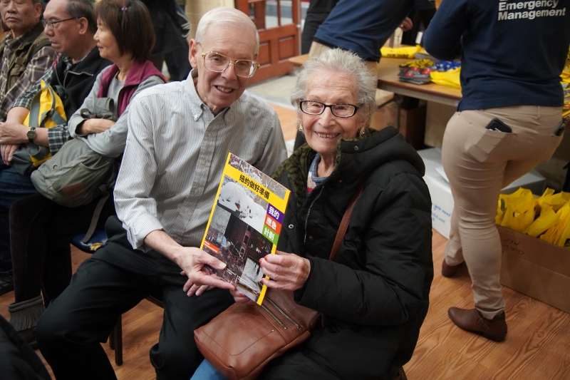 Two seniors hold up a Ready NY guide