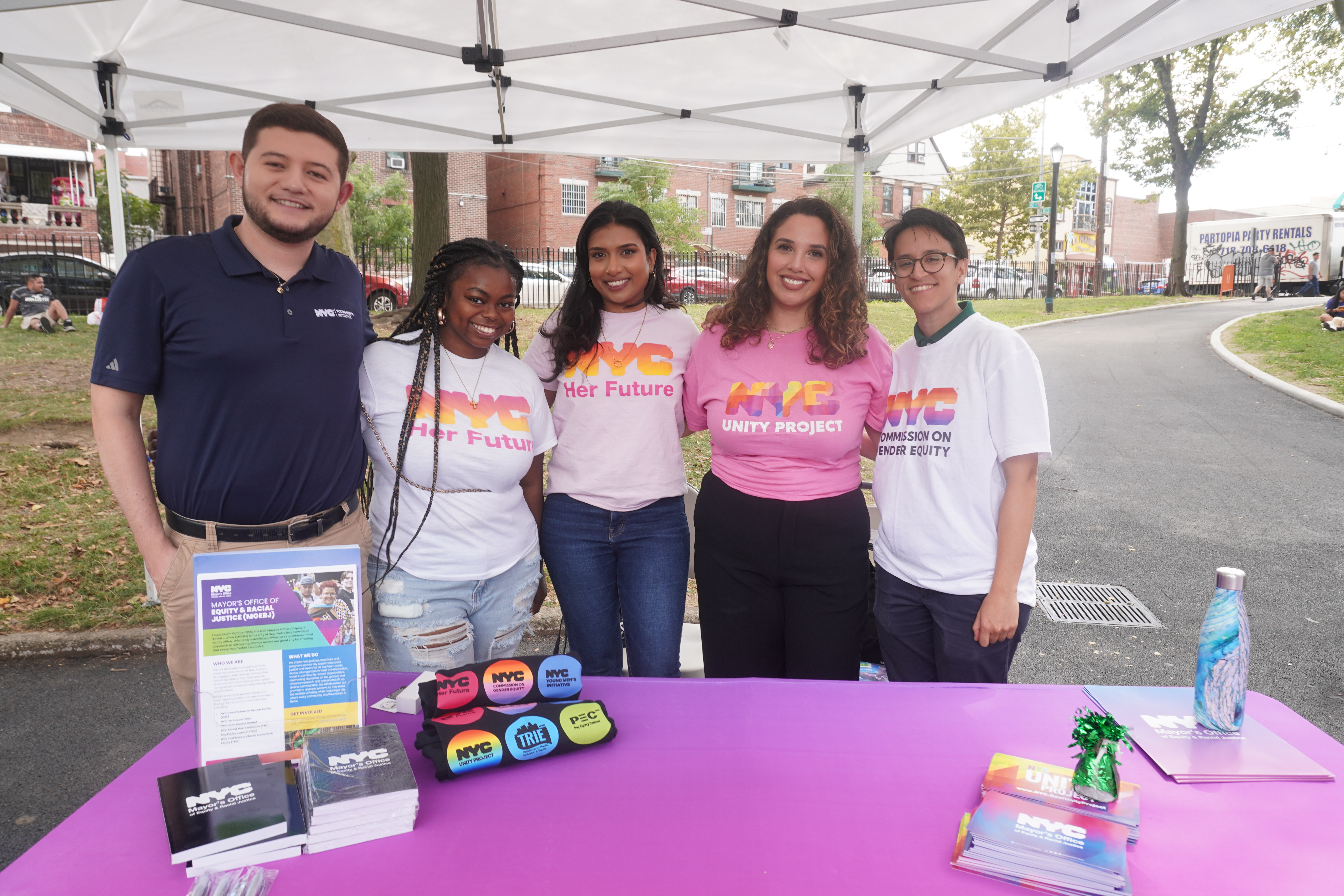 MOERJ staffers at resource fair posed in front of the agency's table with flyers and swag