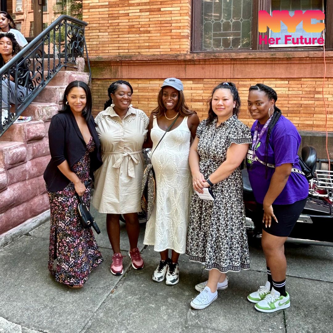 Five women standing in front of a brownstone posing.