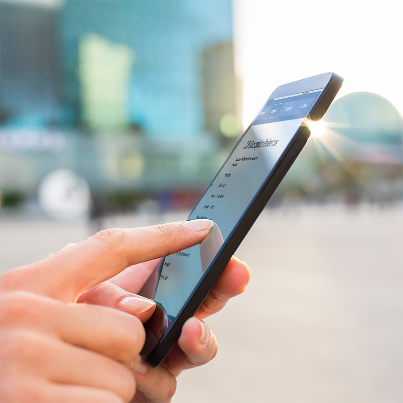 Photo of a woman's hand pointing at a mobile device screen