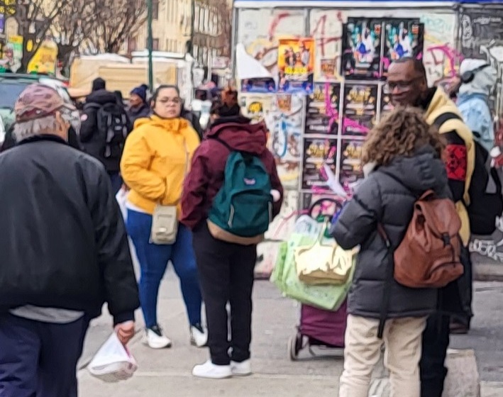 NYC Commission on Gender Equity staff giving out the 16 Days toolkit to community member on a sidewalk in Flatbush, Brooklyn.