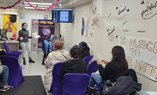NYC Commission on Gender Equity staff member presents to a group of women.