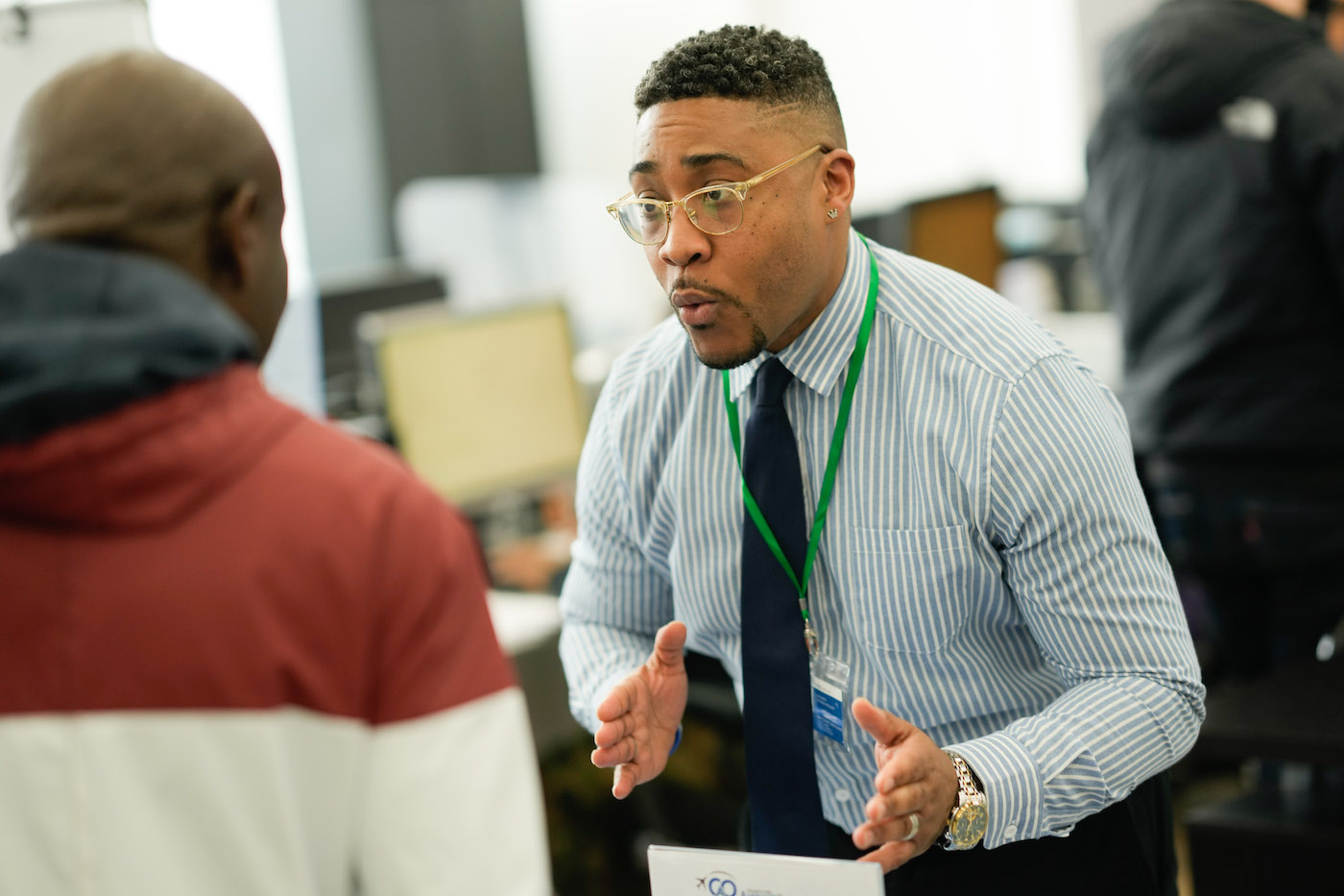 A career advisor in a dress shirt and tie speaks with a job applicant