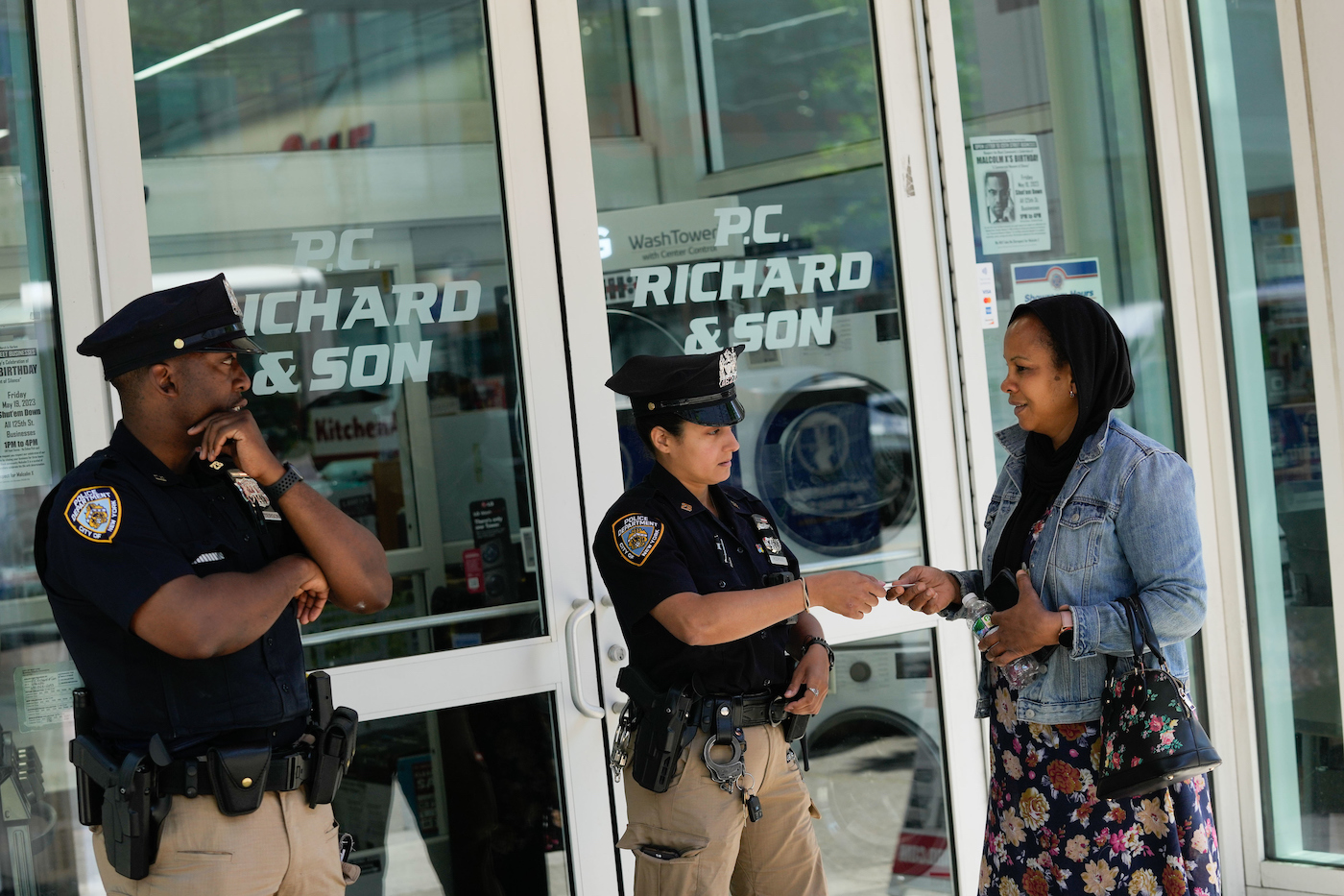 Two NYPD officers, one male, one female, on patrol outside a PC Richards in Harlem.