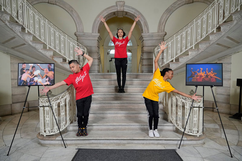 Three people performing dance at the City Hall staircase