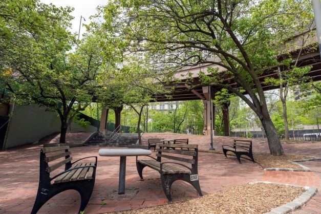 Benches and tables in a public space under the Brooklyn Bridge opening