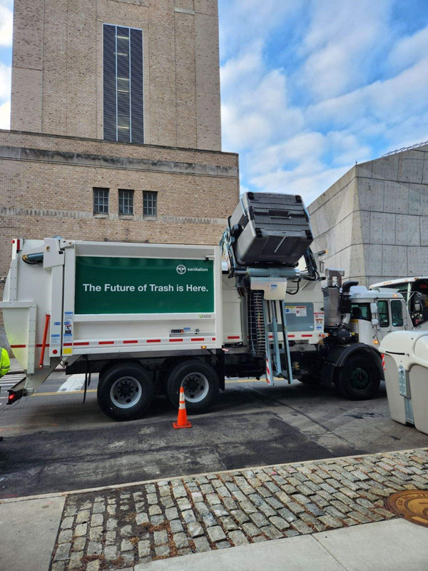 A garbage truck is uploading trash from the trash container