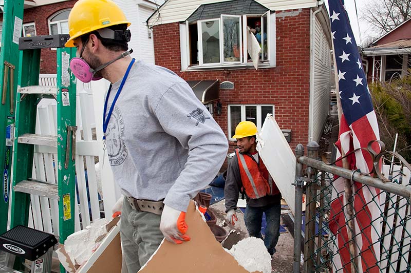 construction workers carrying away debris from inside a house