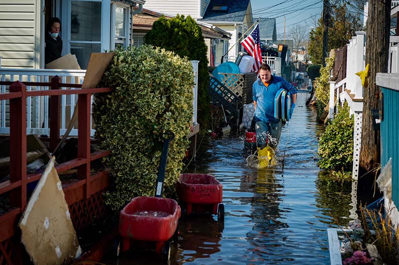 man in wading through flooded alley between houses