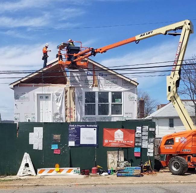 House being rebuilt with workers on the roof
