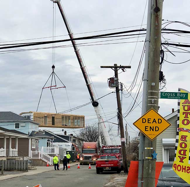 Crane lifting a newly constructed home into place