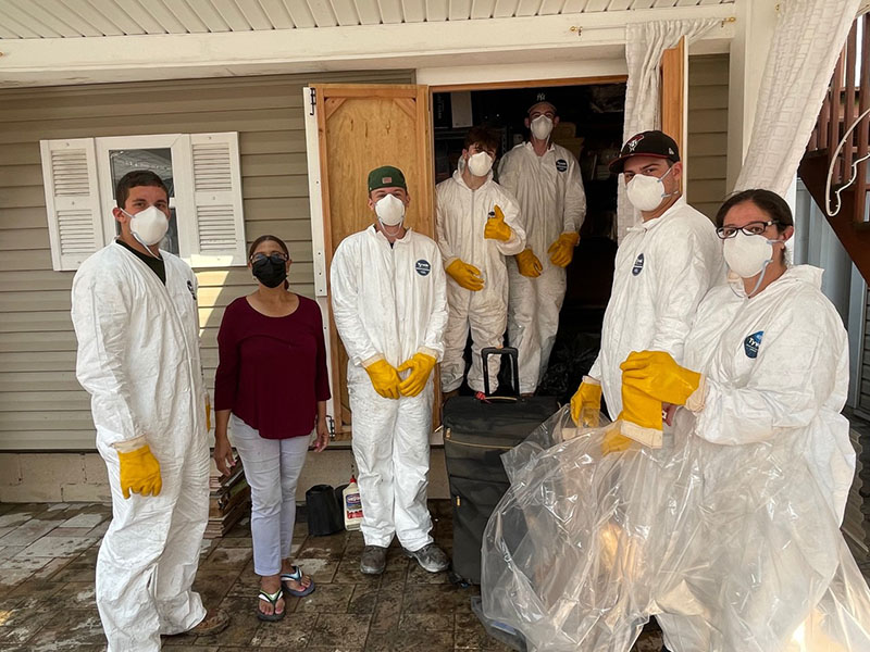 Workers in protective gear in front of a house