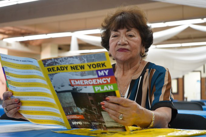 Woman at a table reading a copy of the Ready New York: My Emergency Plan