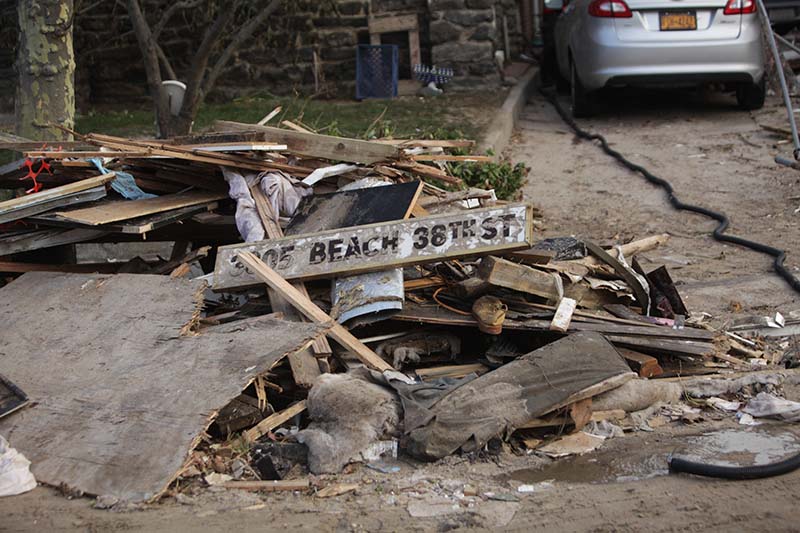 pile of scraps by sidewalk, sign with 3805 Beach 38th St at top of pile