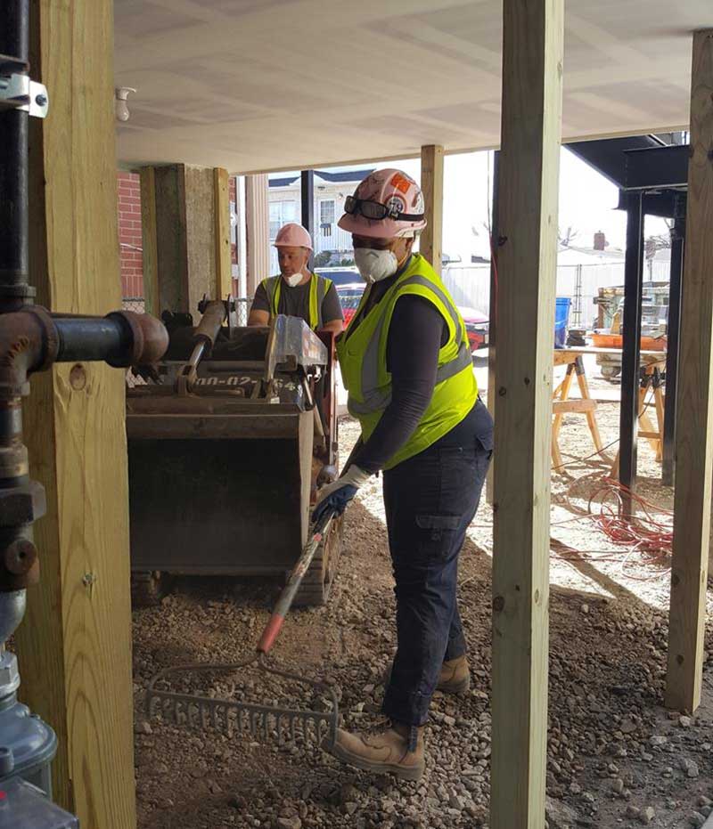 Woman worker in protective gear clearing out rubble