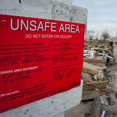 damaged building with red sign stating UNSAFE AREA DO NOT ENTER OR OCCUPY on wall