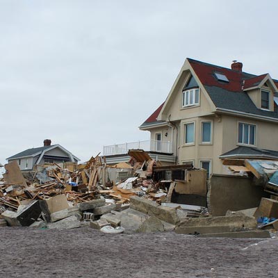 pile of garbage in front of damaged house