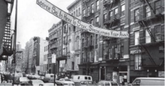 A black-and-white image of a street with a banner stating: "Cooper Sq. Is Here To Stay, Speculators Keep Away."