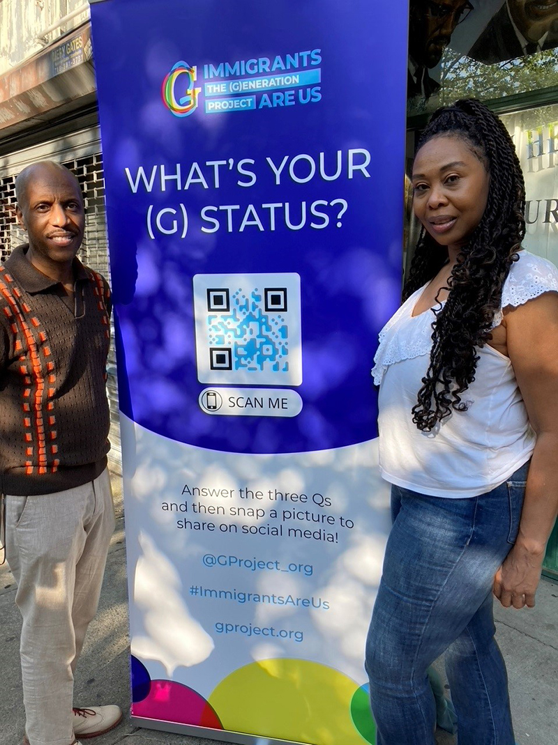 Man and a woman on the street surrounding a poster encouraging individuals to share their (G) Status as part of the Generation Projects collection of immigrant stories.