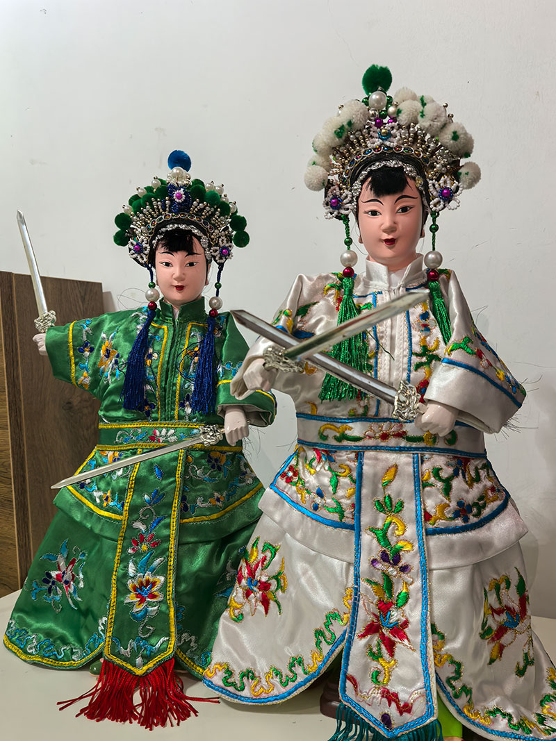 Two Chinese dolls dressed in traditional Chinese clothes holding sword.