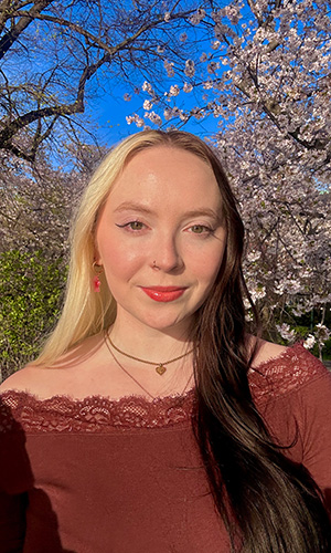 Celia Deming-Bernstein smiling and standing in a park
