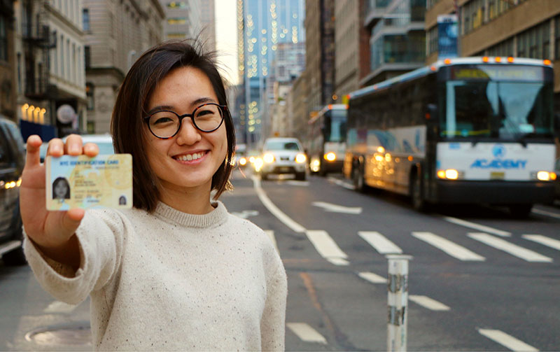 Woman holding an IDNYC card on the street