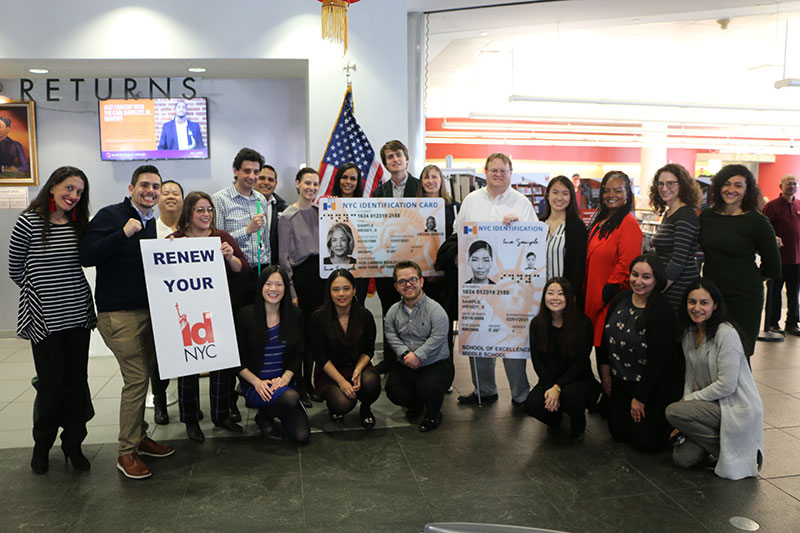 Group of people posing for a photo holding IDNYC signs