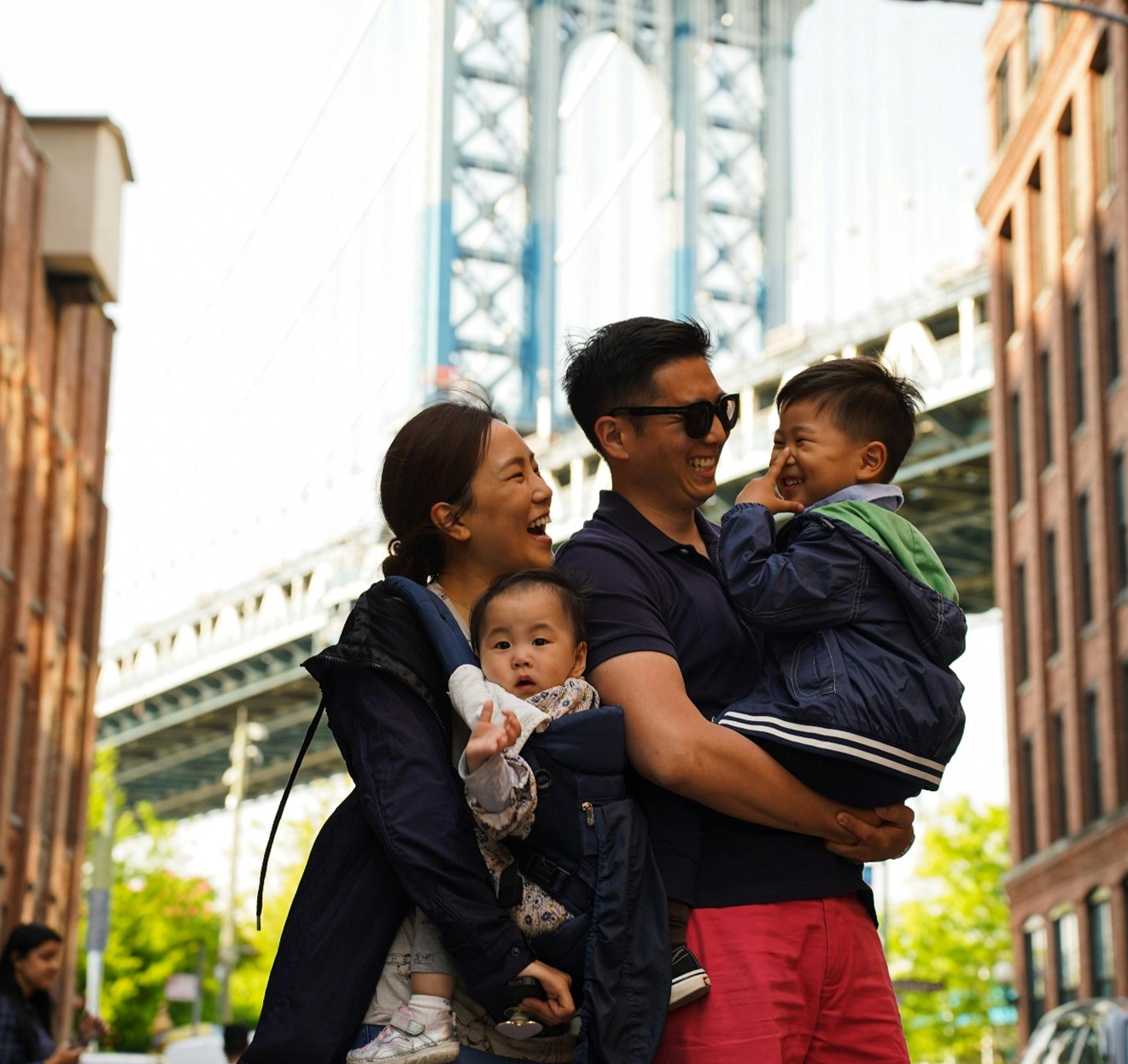 a asian family couple, each carrying a child on their arms.