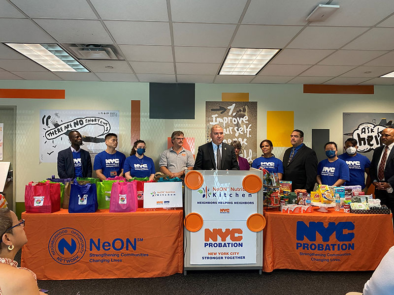 People standing behind orange tables with NeON and NYC Probation logos.