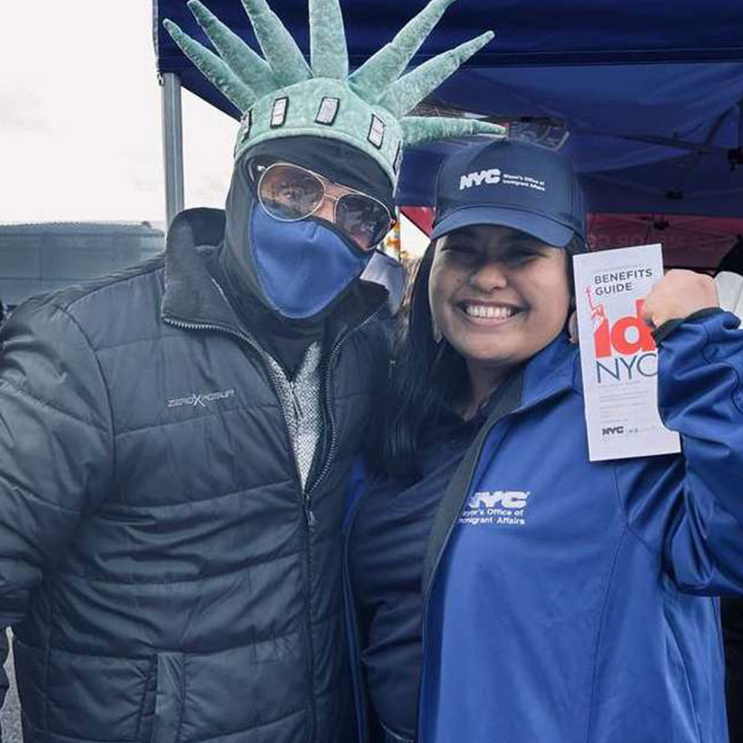 a woman with smile holding high a IDNYC card brochure