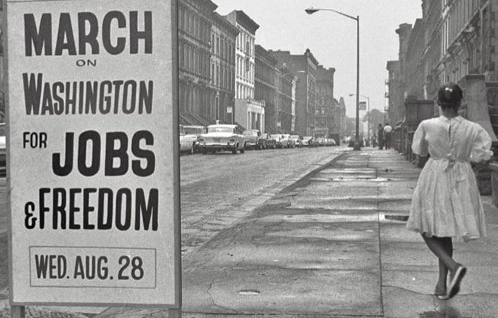 Black and white photo of girl standing next to sign that says March on Washington for Jobs & Freedom