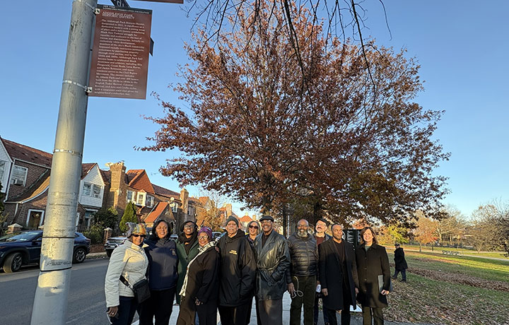 Photo of smiling people standing next to a marker 