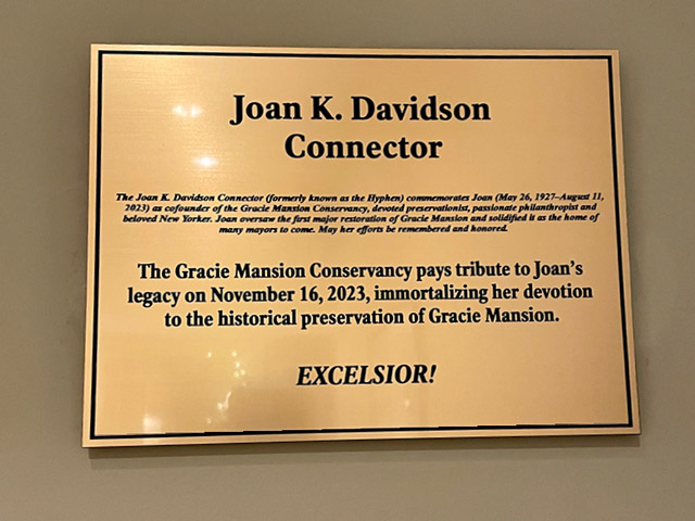 Photo of a plaque on wall, text includes “Joan K. Davidson Connector” and also “The Gracie Mansion Conservancy pays tribute to Joan’s legacy on November 16, 2023, immortalizing her devotion to the historical preservation of Gracie Mansion.  Excelsior!”