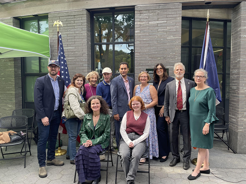 Group of smiling people stand in front of building