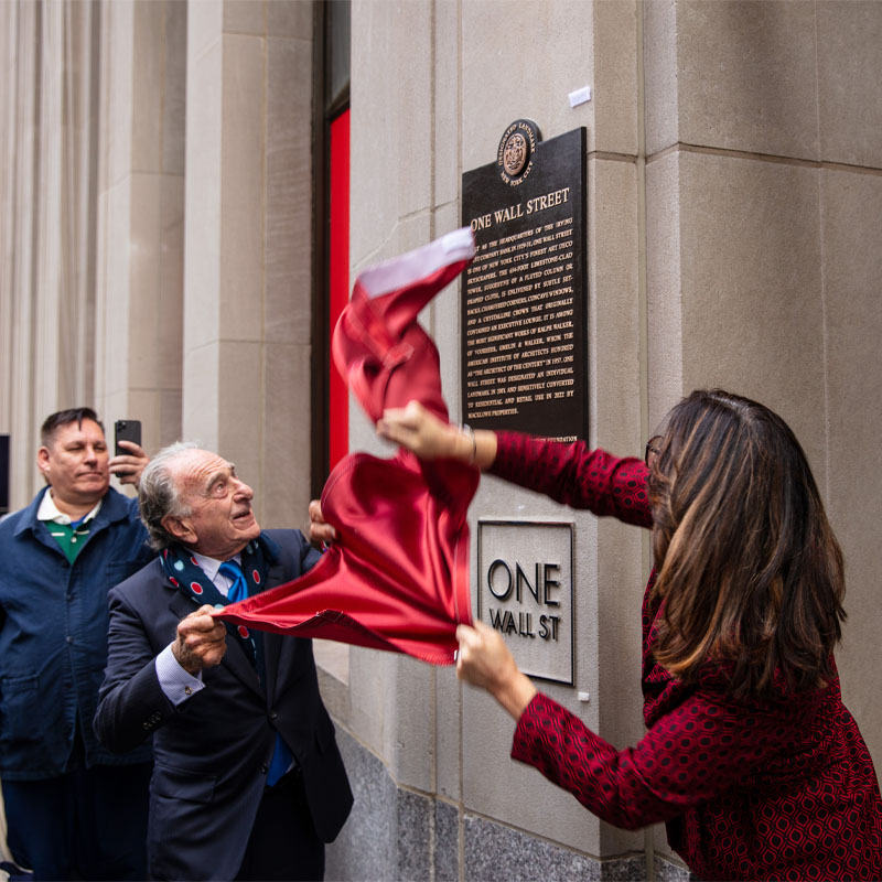 LPC Chair Carroll and Macklowe Properties Founder and Chair Harry Macklowe pull a red cover off a bronze plaque mounted on the building’s exterior wall