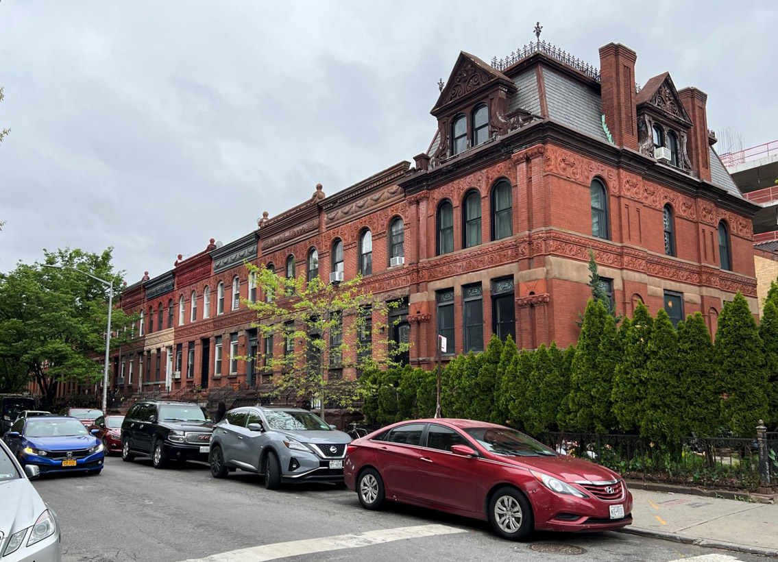 a red buildings across the street and cars lining up at the sidewalk