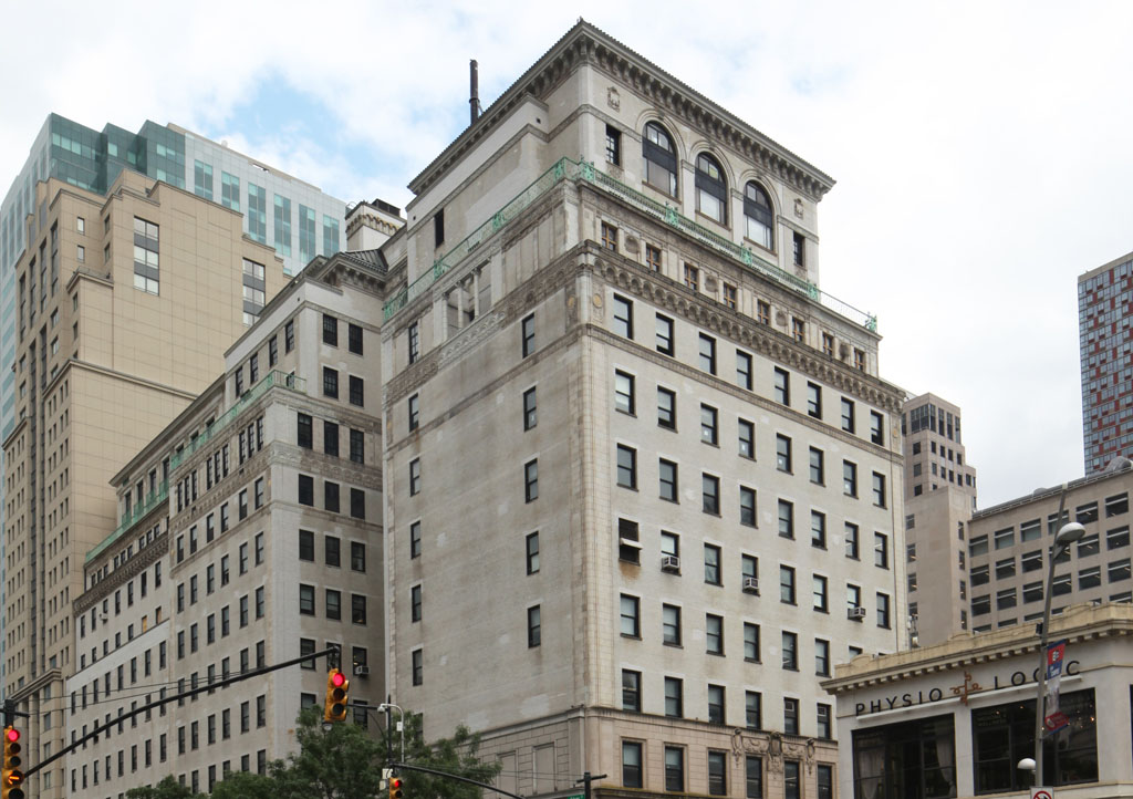 Tan historic building with sky in background and traffic light in foreground