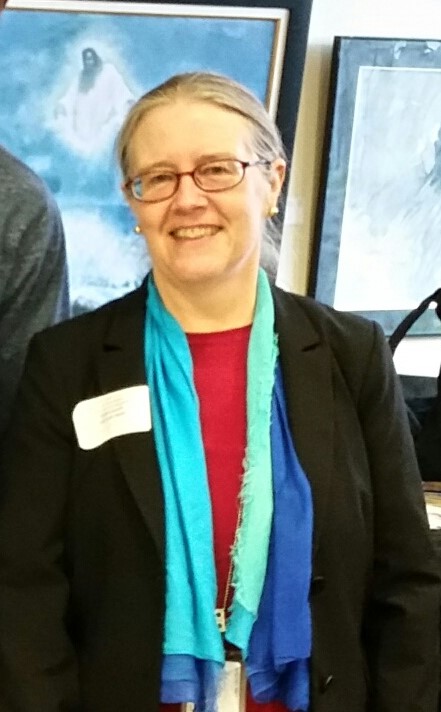 Photo of a smiling woman wearing glasses and a colorful scarf 