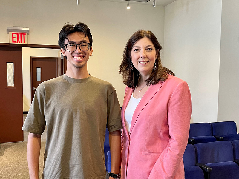 Two smiling people with blue auditorium seats in the background