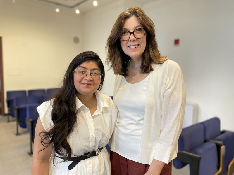 Two smiling people with blue auditorium seats in the background