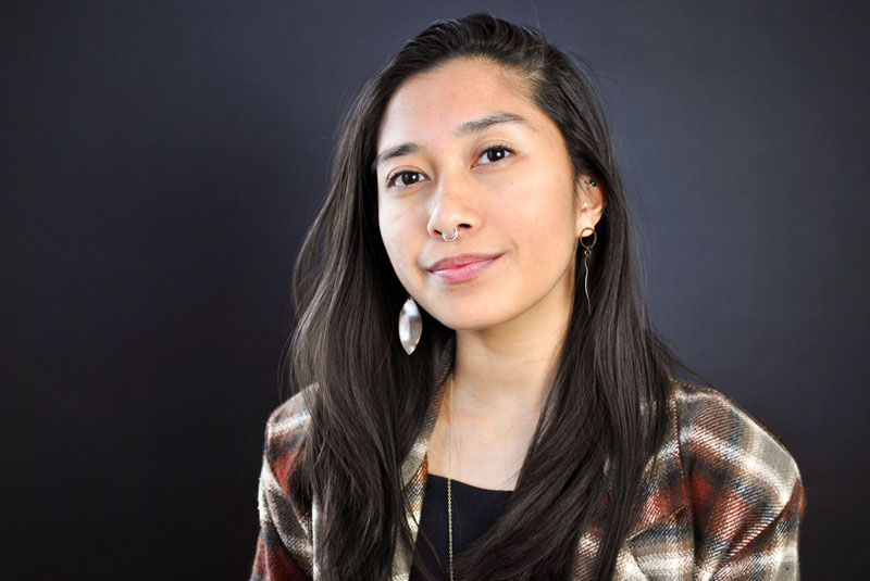 Person in plaid shirt standing in front of black background