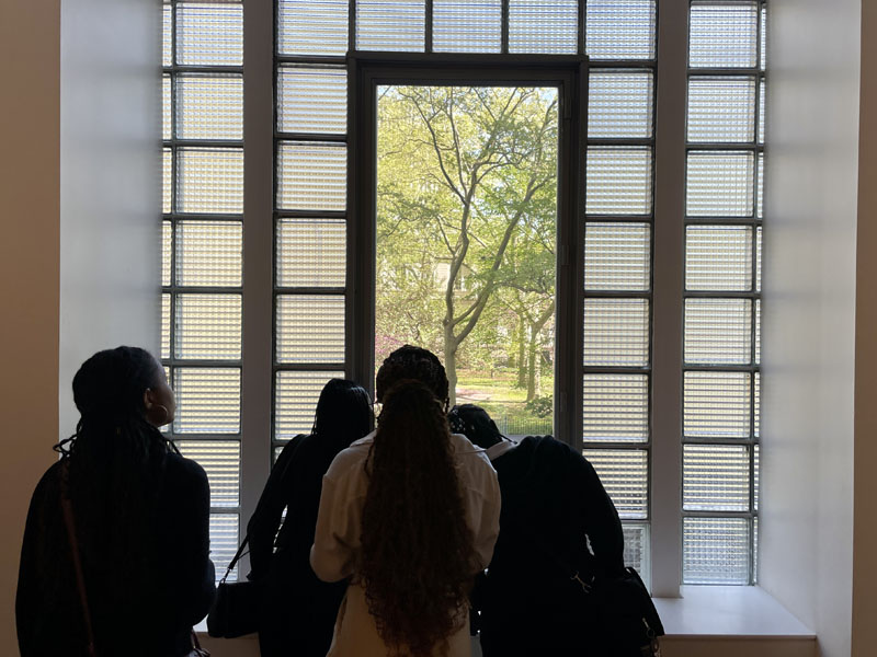 Group of people looking out a window, trees visible in the background
