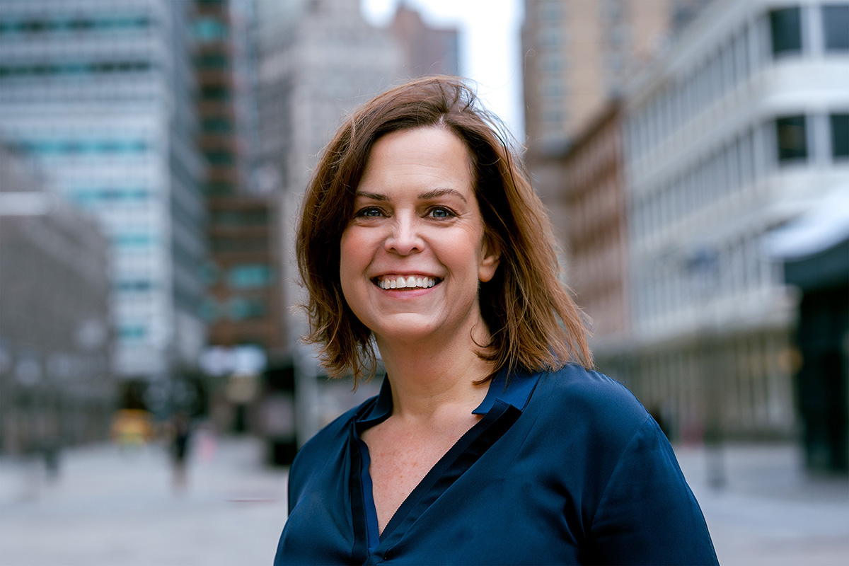 Color photo of a smiling person with cityscape in the background