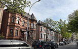 Color photo of three historic buildings: from left to right, a three story brick building, a church, and a four story brick building 