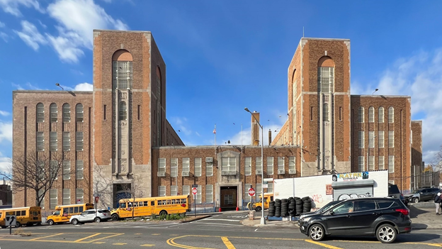 Outside of Gompers Industrial high school; a large brown building with school buses outside