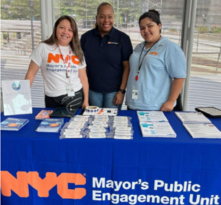 Three woman standing behind the P E U's outreach booth.