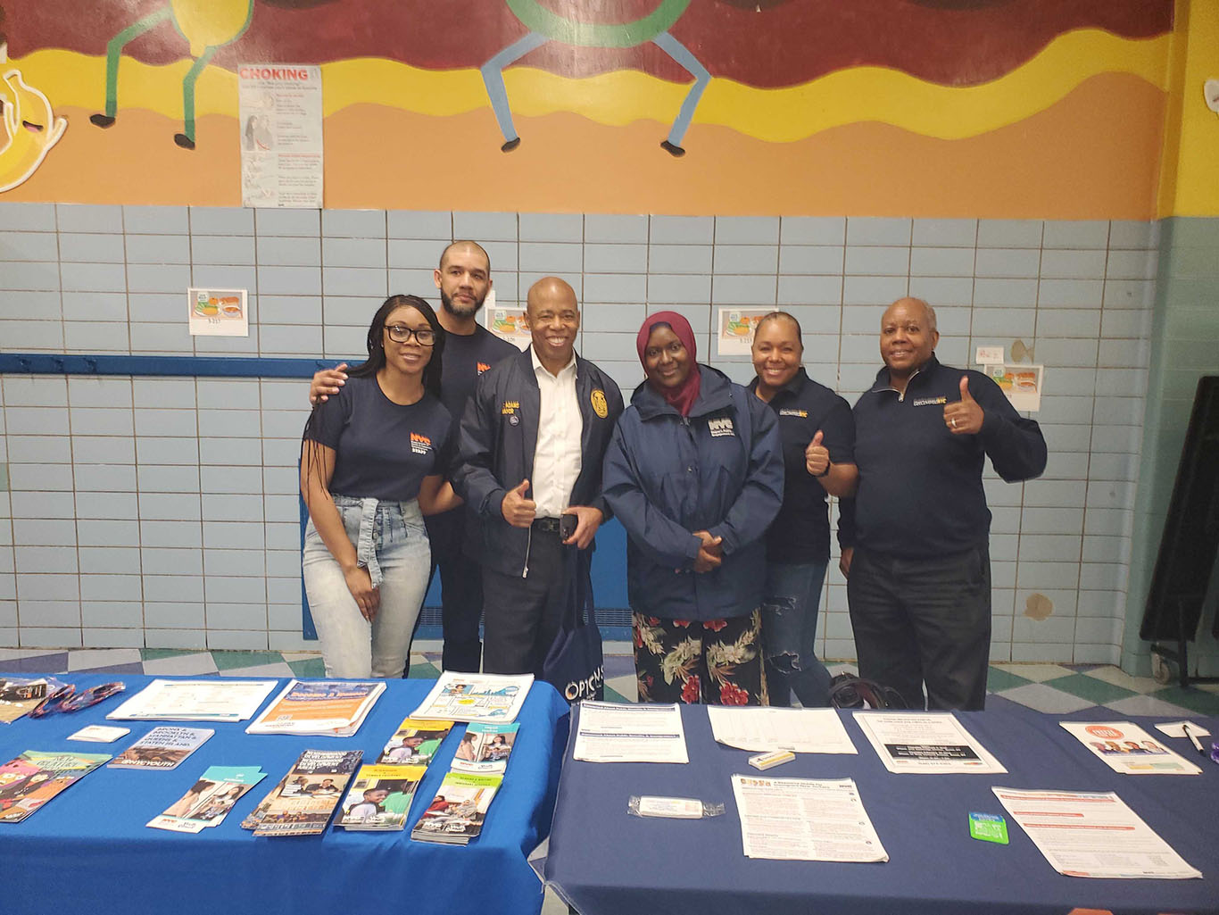 Five PEU Specialists wearing PEU merch stand as a group and pose with NYC Mayor Eric Adams.