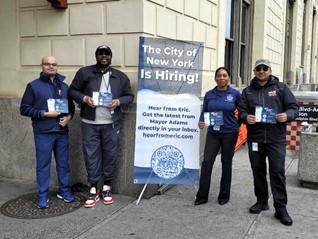 A group of four people holding a PEU's campaign materials at a PEU outreach site.