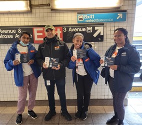 A group of four people holding a PEU's campaign materials at a subway exit.
